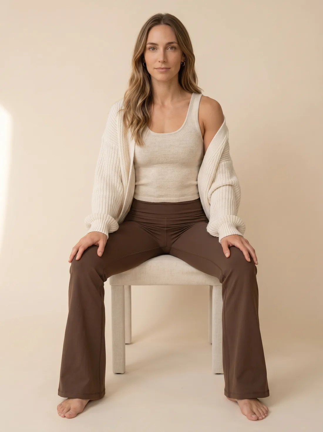 Hanna, imagen de marca de Women Essential, sentada con cardigan crema sobre fondo neutro
